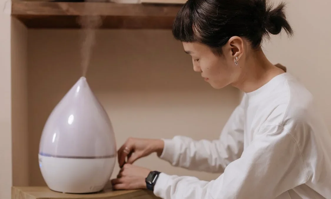 https://www.pexels.com/photo/a-woman-in-white-sweater-sitting-beside-the-wooden-table-with-humidifier-7417504/