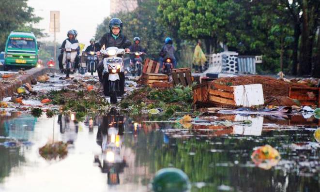 Pengendara bermotor menghundari tumpukan barang dagangan yang rusak akibat banjir di Pasar Gedebage, Jalan Soekarno-Hatta, Kota Bandung, Rabu (8/6).