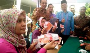 memperlihatkan bantuan tunai PKH setelah melakukan pencairan simbolis.