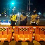 Petugas Kepolisian tampak sedang berjaga disalah satu ruas jalan yang terkena rekayasa penutupan mulai pukul 21.00 hingga 06.00 WIB.