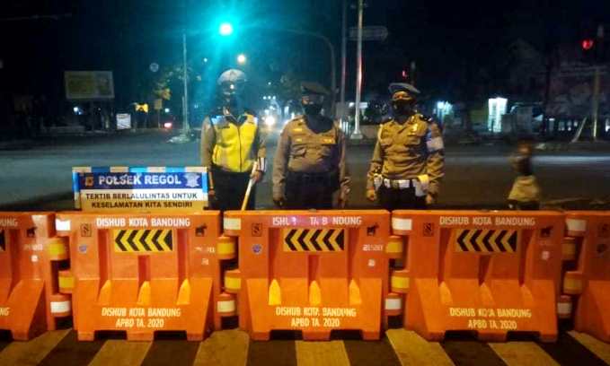 Petugas Kepolisian tampak sedang berjaga disalah satu ruas jalan yang terkena rekayasa penutupan mulai pukul 21.00 hingga 06.00 WIB.