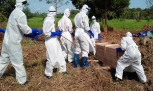 Petugas dari Dinas Kesehatan menggunakan Alat Pelindung Diri (APD) lengkap, tampak sedang memakamkan jenazah yang kematiannya akibat terpapar virus korona.