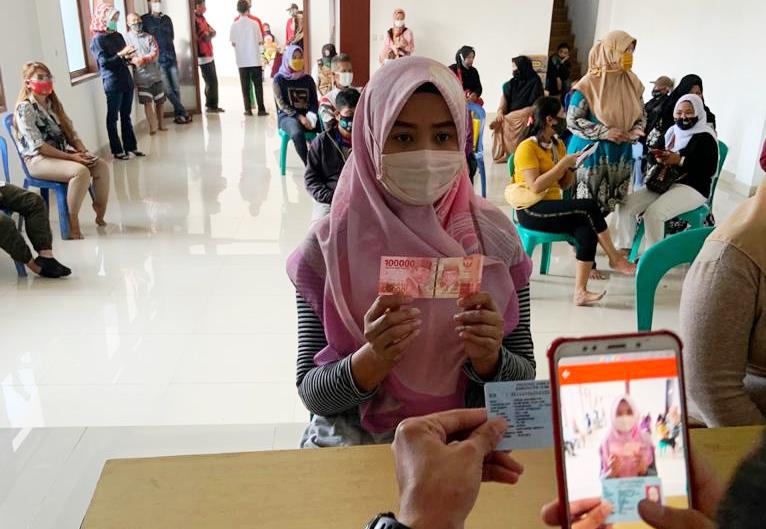 TERIMA BANTUAN: Seorang petugas saat mengambil gambar sebagai bukti penyerahan bantuan bagi warga terdampak korona. (ILUSTRASI)