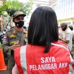 Seorang warga yang kedapatan tidak menggunakan masker saat beraktivitas di luar mendapat hukuman dari para petugas yang sedang melaksanakan razia protokol kesehatan.