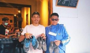 Founder Orangbike Messenger, Sandi Warasastra (kiri) saat menerima sumbangan sepatu. (@orangbikemessenger/Instagram)