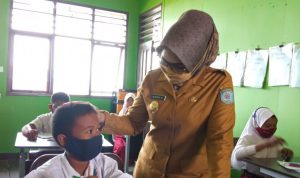 TATAP MUKA: Seorang ibu guru tampak memberikan penjelasan materi mata pelajaran kepada salah satu siwa di kelas saat simulasi pembelajaran tatap muka.