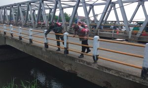 Petugas Polisi dan TNI sedang mengecek badan jembatan yang mengalami keretakan