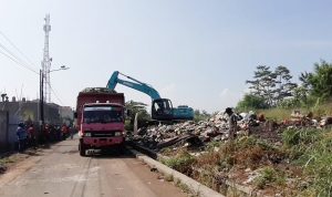 Truk pengangkut sampah sedang melakukan evakuasi sampah dengan menggunakan alat berat.
