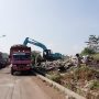 Truk pengangkut sampah sedang melakukan evakuasi sampah dengan menggunakan alat berat.