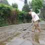 Seorang warga tengah membersihkan jalan dari kotoran sapi yang terbawa arus air hujan di Desa Kayu ambon lembang, beberapa waktu lalu. (Foto: Wisnu/ JabarEkspres)