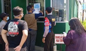 Lurah Utama Ceppy Rustiawan menempelkan stiker pada salah satu pabrik di Kelurahan Utama.
