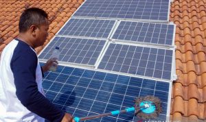 Seorang warga pemilik panel surya, Agus Nurokhim, membersihkan panel Pembangkit Listrik Tenaga Surya (PLTS) di atap rumahnya di Sragi, Kabupaten Pekalongan, Jawa Tengah, Minggu (1/9/2019). ANTARA FOTO/Harviyan Perdana Putra/foc.