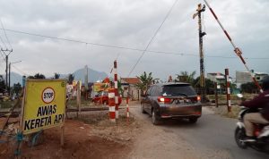 Kendaraan melintas di jalur rel Kereta Api Cimekar tanpa palang pintu otomatis.