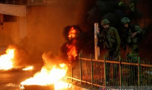 Arsip--Tentara Israel berdiri di samping pembakaran ban saat warga Palestina mengambil bagian dalam protes anti-Israel atas ketegangan di Yerusalem, di Hebron di Tepi Barat yang diduduki Israel, Senin (26/4/2021). ANTARA FOTO/REUTERS/Mussa Qawasma/AWW/sa.