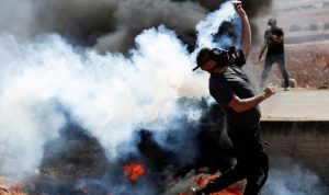 Warga Palestina mengembalikan tabung gas air mata yang ditembakkan pasukan Israel dalam aksi protes menentang permukiman Israel di Beit Dajan, Tepi Barat yang diduduki Israel, Jumat (22/10/2021). (ANTARA/Reuters)