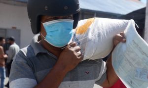 Warga membawa sekarung beras seusai penyaluran di Kantor PT POS Indonesia, Banda Aceh, Aceh, Senin (26/7/2021). (ANTARA FOTO/Ampelsa/foc.)