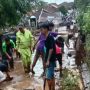 Warga desa di Kecamatan Sukawening tengah membersihkan jalan setelah diterjang banjir bandang