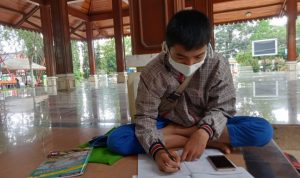 Disela kesibukan Ragil berjualan, dia tidak meninggalkan tugasnya sebagai pelajar untuk mengerjakan tugas dari sekolah. (Istimewa)