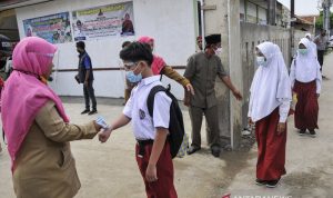 Arsip Foto. Seorang guru mengukur suhu tubuh siswa yang hendak mengikuti pembelajaran tatap muka di SDN Karang Raharja 02, Cikarang, Kabupaten Bekasi, Jawa Barat. (ANTARA FOTO/Fakhri Hermansyah/rwa)