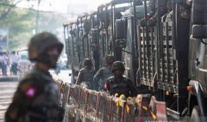Serangan Maut di Myanmar Sebabkan Dua Relawan Menghilang Ilustrasi: Tentara berdiri di samping kendaraan militer ketika orang-orang berkumpul untuk memprotes kudeta militer di Yangon, Myanmar, 15 Februari 2021. (REUTERS/Stringer)