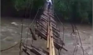 Tangkapan layar video yang memperlihatkan kondisi jembatan yang nyaris putus sangat membahayakan seorang pelajar yang berusaha melintasinya.