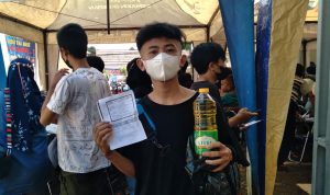 Salah seorang warga peserta vaksinasi di Polsek Cicalengka yang mendapat hadiah minyak goreng usai divaksin. (Jabar Ekspres)