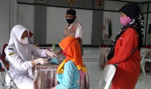 Seorang tenaga kesehatan tengah memeriksa kondisi anak peserta vaksin di Balai Desa Sindangpakuon, Kecamatan Cimanggung, Kabupaten Sumedang. (Jabar Ekspres)