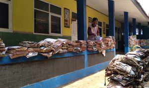 Kepala Sekolah SDN 07 Rancaekek, Suparyana tengah memilah dan menjemur buku yang rusak serta basah akibat banjir bandang. (Jabar Ekspres)