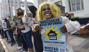 Peduli Lingkungan, Puluhan Anak Muda Kota Bandung Gelar Aksi Peduli Iklim dan Alam Foto: Seorang pengunjuk rasa membentangkan poster di sekitar Gedung Merdeka, Jalan Asia Afrika, Bandung, Jumat (25/3). (Foto: Dimas Rachmatsyah)