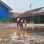 Dua anak tengah bermain lumpur di lapangan upacara SDN 07 Rancaekek pasca diterjang banjir. (Jabar Ekspres)