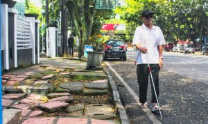 TUNANETRA: Seorang penyandang disabilitas tunanetra saat menggunakan bahu jalan, lantaran trotoar rusak dan membahayakan. (Deni/Jabar Ekspres)