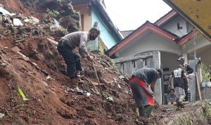 Anggota Kepolisian serta warga tengah membersihkan material tanah pasca TPT di Dusun Haur Koneng, Desa Ciherang, Kecamatan Sumedang Selatan, Kabupaten Sumedang ambrol, Kamis (12/5).