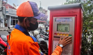 Deni Mulyadi tengah mengoperasikan mesin parkir di Jalan Braga, Senin (30/5). (Deni/Jabar Ekspres)