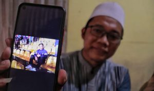 Ahmad, (40), salah satu keluarga Asep Ahmad Solihin, (29), memperlihatkan potret Asep saat duduk di stadion menyaksikan pertandingan dari Persib Bandung. (Deni/Jabar Ekspres)