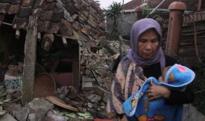Gempa Bumi Cianjur, Porak-porandakan Ratusan Rumah MENYELAMATKAN DIRI: Seorang warga sambil menggendong anaknya melintas runtuhan bangunan yang terdampak gempa bumi Cianjur Senin 21 November 2022. (SANDIKA FADILAH/JABAREKPRES.COM)