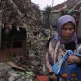 MENYELAMATKAN DIRI: Seorang warga sambil menggendong anaknya melintas runtuhan bangunan yang terdampak gempa bumi Cianjur Senin 21 November 2022. (SANDIKA FADILAH/JABAREKPRES.COM)