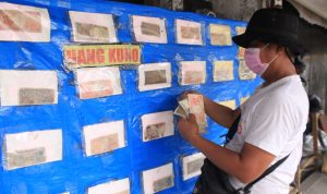 BARANG AKTIK: Burhanuddin sedang merapikan sejumlah koleksi uang kuno yang dipajang di Jalan Asia Afrika, Bandung, Rabu 1 Februari 2023. (HENDRIK MUCHLISON/JABAR EKSPRES)