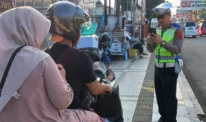 Petugas kepolisian saat menilang pengendara sepeda motor menggunakan ETLE, Sumber: Istimewa.