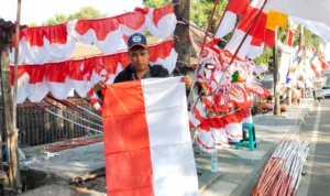 Omzet Tembus Rp5 Juta Per Hari, Penjual Bendera Ini Betah Berjualan di Sumedang Rehan alias Ubek (33) sedang memegang bendera Merah Putih di lapak tempatnya berjualan di Sumedang, Jum'at 4 Agustus 2023.