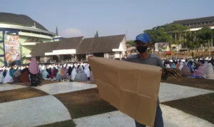 Atang (61) berjualan alas kertas saat pelaksanaan shalat Istisqa di lapang merdeka kota Sukabumi. Foto: Riki/Jabar Ekspres