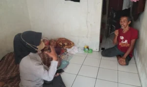 Toto Muswanto berada di kontrakannya bersama sang istri, Eti Kusniati, yang terbaring tak berdaya karena sakit parah saat dijenguk oleh salah satu relawan kemanusiaan, Jumat 15 Desember 2023. (Cecep Herdi/Jabar Ekspres)