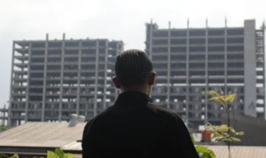 Warga setempat sedang memandangi gedung terbengkalai di Bandung Timur, yakni Rusunami Cisaranten Bina Harapan.