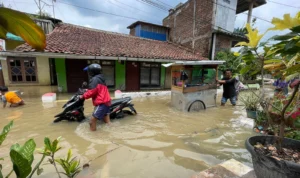 Sungai Citarum Meluap, 8 RW di Kampung Bojong Asih Terendam Banjir Seorang pengendara motor dan pedagang yang melintasi banjir di Kampung Bojong Asih, Dayeuhkolot, Kabupaten Bandung, Jumat (1/12/2023). Foto Agi Jabar Ekspres