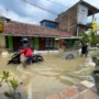 Seorang pengendara motor dan pedagang yang melintasi banjir di Kampung Bojong Asih, Dayeuhkolot, Kabupaten Bandung, Jumat (1/12/2023). Foto Agi Jabar Ekspres