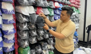 Muhammad Ilham Maulana Pengusaha Topi Custom saat memperlihatkan topi yang akan dicustom untuk para pemesan di rumah produksinya di Desa Cigondewah Hilir, Kecamatan Margaasih, Kabupaten Bandung, Jumat (8/12/2023). Foto Agi Jabar Ekspress