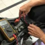 Teknisi sedang mengecek kondisi aki pada sepeda motor.