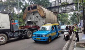 Petugas kepolisian nampak mengatur lalu lintas di samping truk pengangkut mesin pengolah batu bara yang nyangkut di Jalan Dr. Setiabudi / Hendrik Muchlison