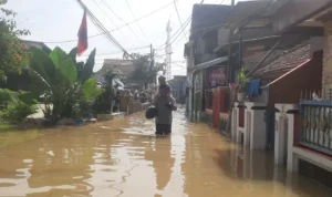 Ribuan Rumah di Kampung Bojong Asih Dayeuhkolot Kembali Terendam Banjir, Warga Minta Penambahan Folder Air Seorang warga saat melintasi banjir yang mengepung Kampung Bojong Asih, Dayeuhkolot, Kabupaten Bandung, Senin (8/1/2024). Foto Agi Jabar Ekspres