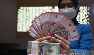 Petugas perbankan menunjukkan uang Dolar AS dan uang Rupiah.