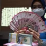 Petugas perbankan menunjukkan uang Dolar AS dan uang Rupiah.